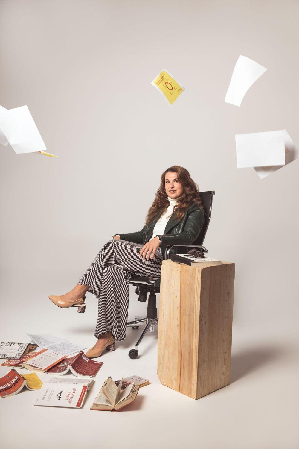 Sarah at a desk with papers in mid-air
