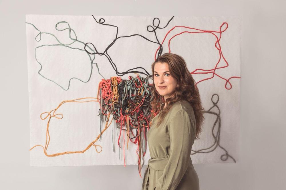 Sarah in front of a tangled-thread artwork